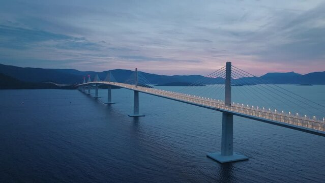 Modern bridge across the Mediterranean sea. Cars crossing the bridge in the evening. Dark blue sea and blue sky. 