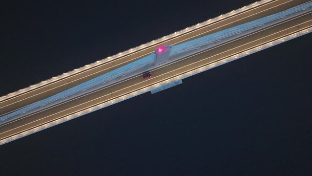 Top-down view of modern bridge with lights across calm dark blue ocean. Majestic bridge connecting land. 