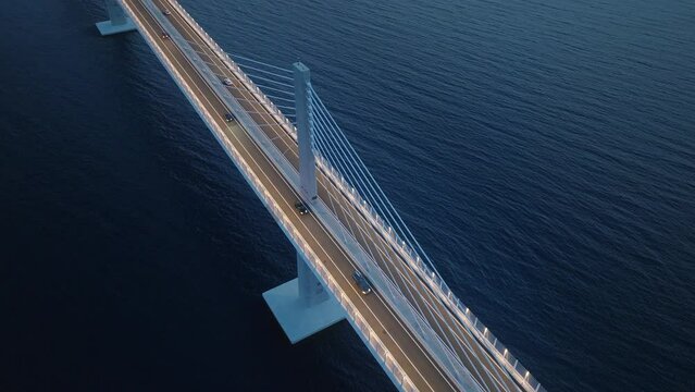 Top-down aerial view of modern bridge across the dark blue sea at night. Cars crossing the bridge over the Mediterranean sea. 