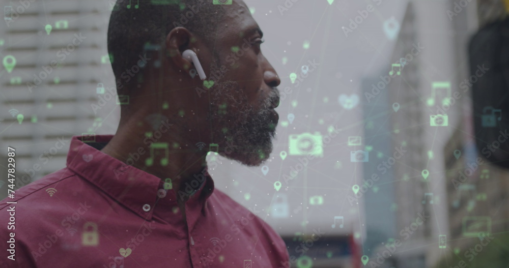 Wall mural Image of networks with digital icons over african american man using smartphone in city