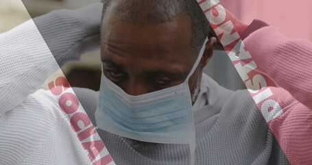Image of covid 19 social distancing text over african american man putting face mask on