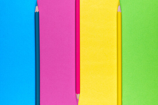 Drei Buntstifte mit farblich passendem Buntpapier zum Thema Kreativität, Malen und Basteln
