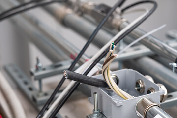 Stripped electrical wires are prepared for installation on industrial machinery. The image captures the intricate details of the setup process in an industrial environment. Electrical Wiring
