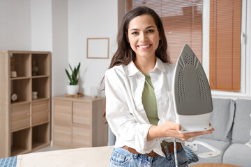 Pretty young woman with modern iron at home