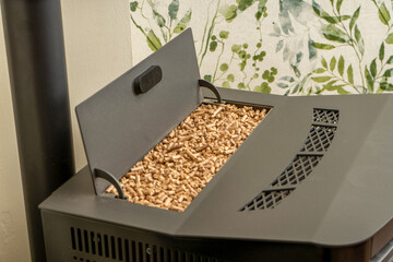 Horizontal image of a pellet stove with a full hopper, sustainable heat. Green energy concept.