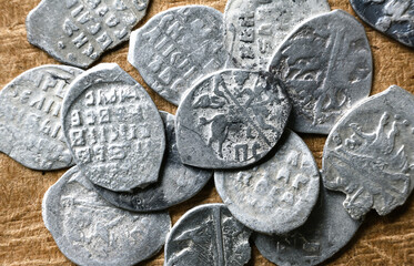 Ancient Russian coins 16th century close-up, pile of silver money of Tsar Ivan IV the Terrible. Top view of metal flakes on vintage background. Concept of old Russia, antique, collection - obrazy, fototapety, plakaty