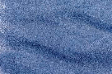 Tanned leather is painted blue. Blue leather background macro.