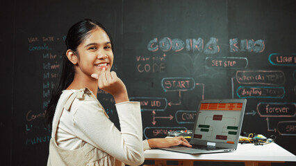 Smart girl using laptop coding or programing system at blackboard. Happy highschool student working...