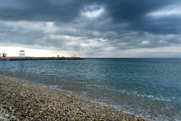 Scenic landscape of the beach and dark blue sea, cloudy sky before a thunderstorm