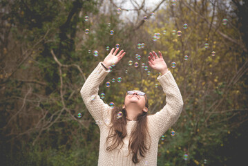 Chica jugando con burbujas en el bosque