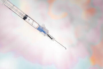Medical syringe and needle with fluid dripping out of needle.