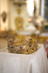 A golden crown with precious stones on a tray in a church.