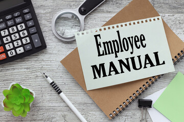 EMPLOYEE MANUAL text on the page. notepad near magnifying glass and calculator