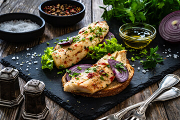 Tasty sandwiches - toasted bread with pickled herrings on and red onion on wooden table

