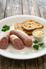 Easter breakfast - boiled white sausages, toasts and horseradish on wooden table 
