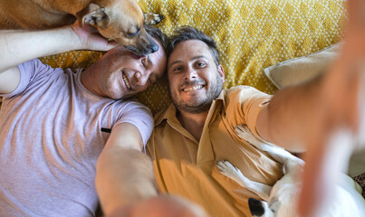 selfie of a homosexual couple with their dogs lying on the floor looking at the camera