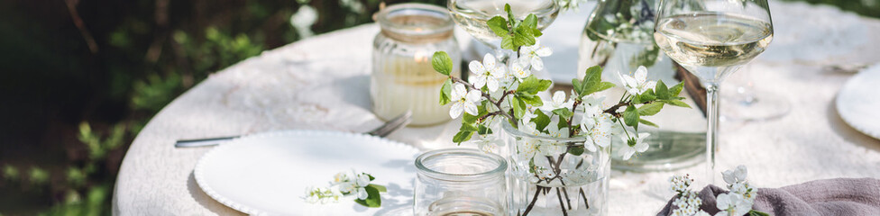 Romantic elegant luxury wedding table decor with white fresh spring blooming cherry apple tree flowers. Glass, candles, floral decoration for special marriage holiday event. Zero waste, banner