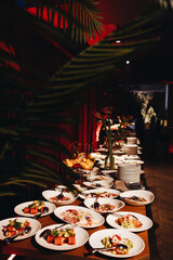 Beautifully decorated catering banquet table with different food snacks and appetizers with sandwich, caviar, fresh fruits on corporate christmas birthday party event or wedding celebration.