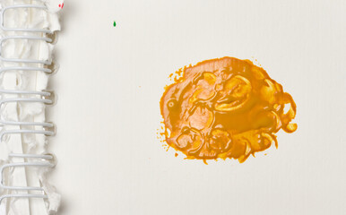Orange paint swatch on a sheet of white paper in a notepad