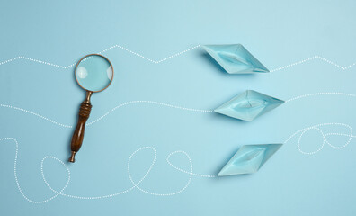 Blue paper boats and a magnifying glass, viewed from above
