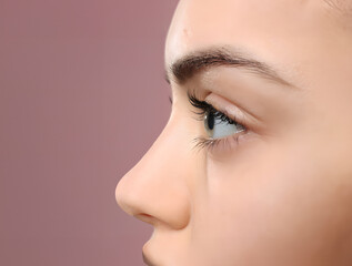 Extreme close up profile side view of female model face with perfect skin on pink background.