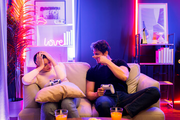 Man winner fighting gamer on video game beside woman loser challenge. Couple joyful playing on TV...
