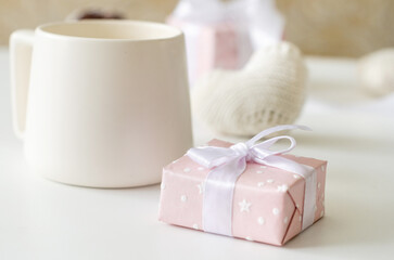 Obraz na płótnie Canvas Pink gift box with a bow and a cup of tea on a white background
