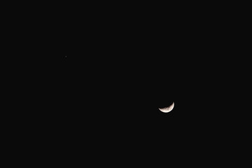 The waxing crescent moon in the night sky. The bottom sliver of the moon is visible as well as the...
