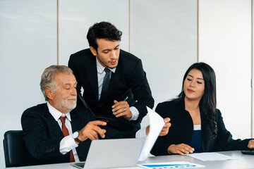 Senior caucasian manager working in office with assistance of young Asian business people and...