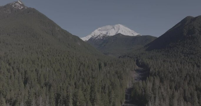 Ungraded wide-angle aerial drone footage of Mount Rainier under blue sky on a sunny winter morning in Washington State.