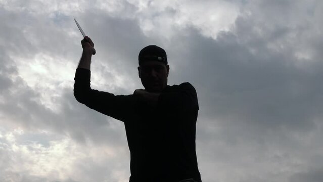 A man performing knife attack aggression: video of a killer or maniac with knife. Martial art Kali Arnis Escrima "cinco tiros". Tactical military knife use. Concept of fighting terrorism