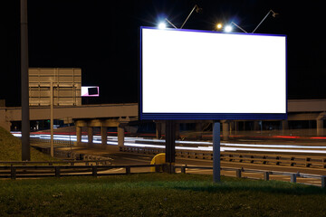 Billboard on one support near a highway on a dark night, tracks from car headlights. Mock-up.