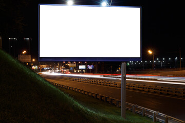 Horizontal billboard against the backdrop of a night highway with tracks from car lights. Mock-up.