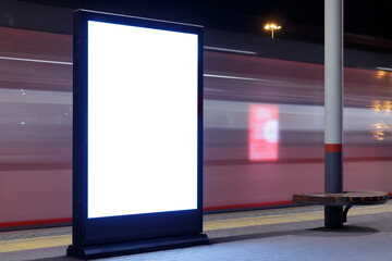 Billboard at a railway station with a fast passing train, motion blur. Mock-up.