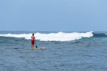 Stand up paddler waiting for waves to surf in the ocean - 744853742