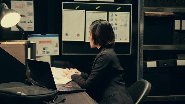 Asian police agent opening criminal investigation at private company, managing law enforcement and criminology. Detective evaluating forensic evidence and archived folders from old cases. Camera B.