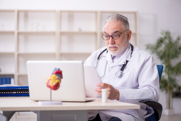 Old male doctor cardiologist working in the clinic
