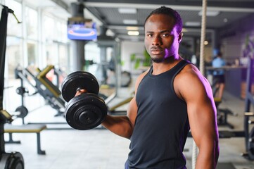Fototapeta na wymiar healthy african man working out with dumbbells in gym