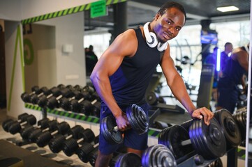 Black Male Athlete Taking Dumbbell From Rack At Gym