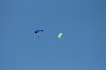 Skydivers with blue and green parachutes in the air