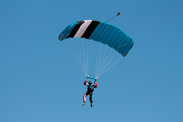 A skydiver with a blue parachute in the air