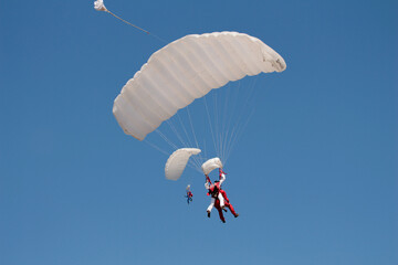 Skydivers with white parachutes in the air