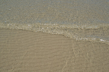 At the beach, gentle ripples caress sand and water, creating a serene and soothing atmosphere