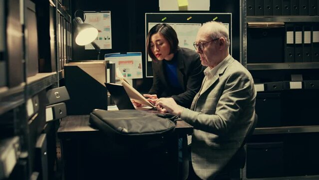 Team members cross reference data to track down potential suspect, using archived records and forensic evidence reports. Officers uncover crucial information to help solve legal case. Camera B.