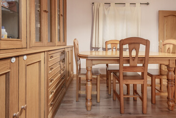 A small living room with wooden furniture and a dining table with matching chairs