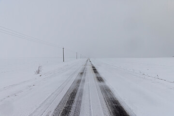 a snow-covered paved road in the winter season in a snowfall