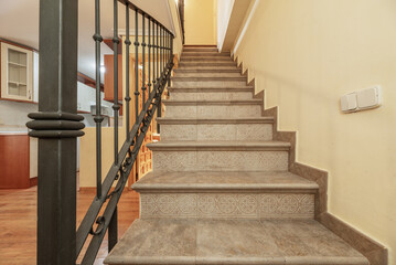 Interior stairs of a duplex residential home with steps with gray tiles and metal railing