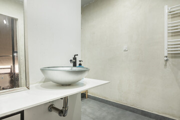 White countertop of a small bathroom with a silver-colored semicircular sink