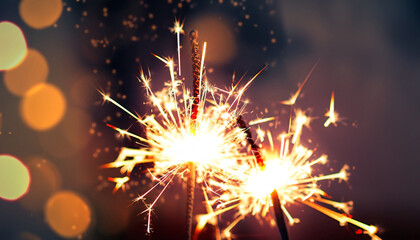 two burning sparklers on blurred background; holiday backdrop for your projects