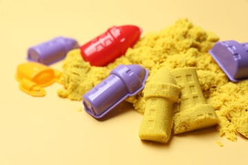 Castle figures made of kinetic sand and plastic toys on beige background, closeup. Space for text